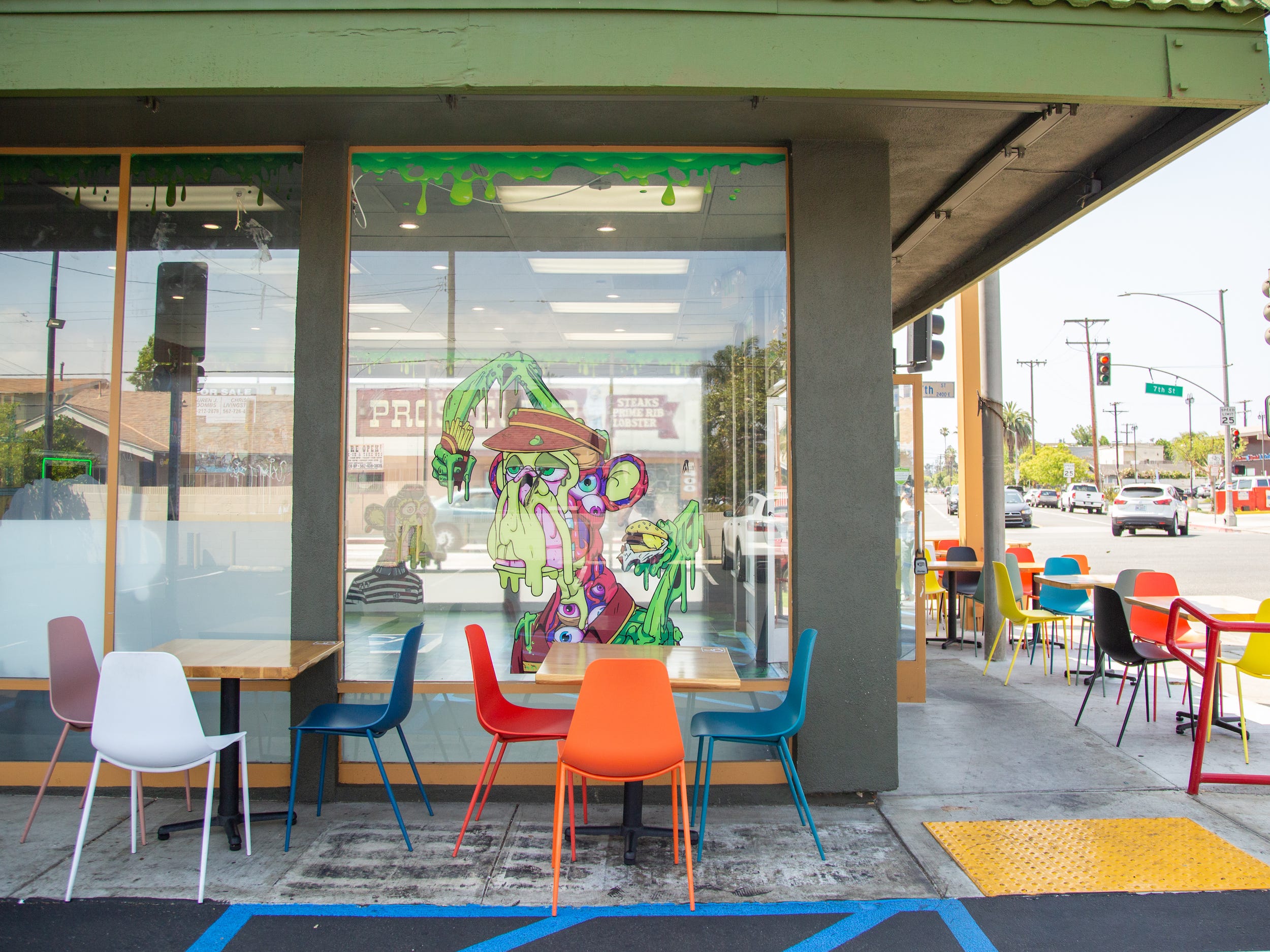 The exterior of the Bored and Hungry store with tables, chairs, a mutant ape decal.