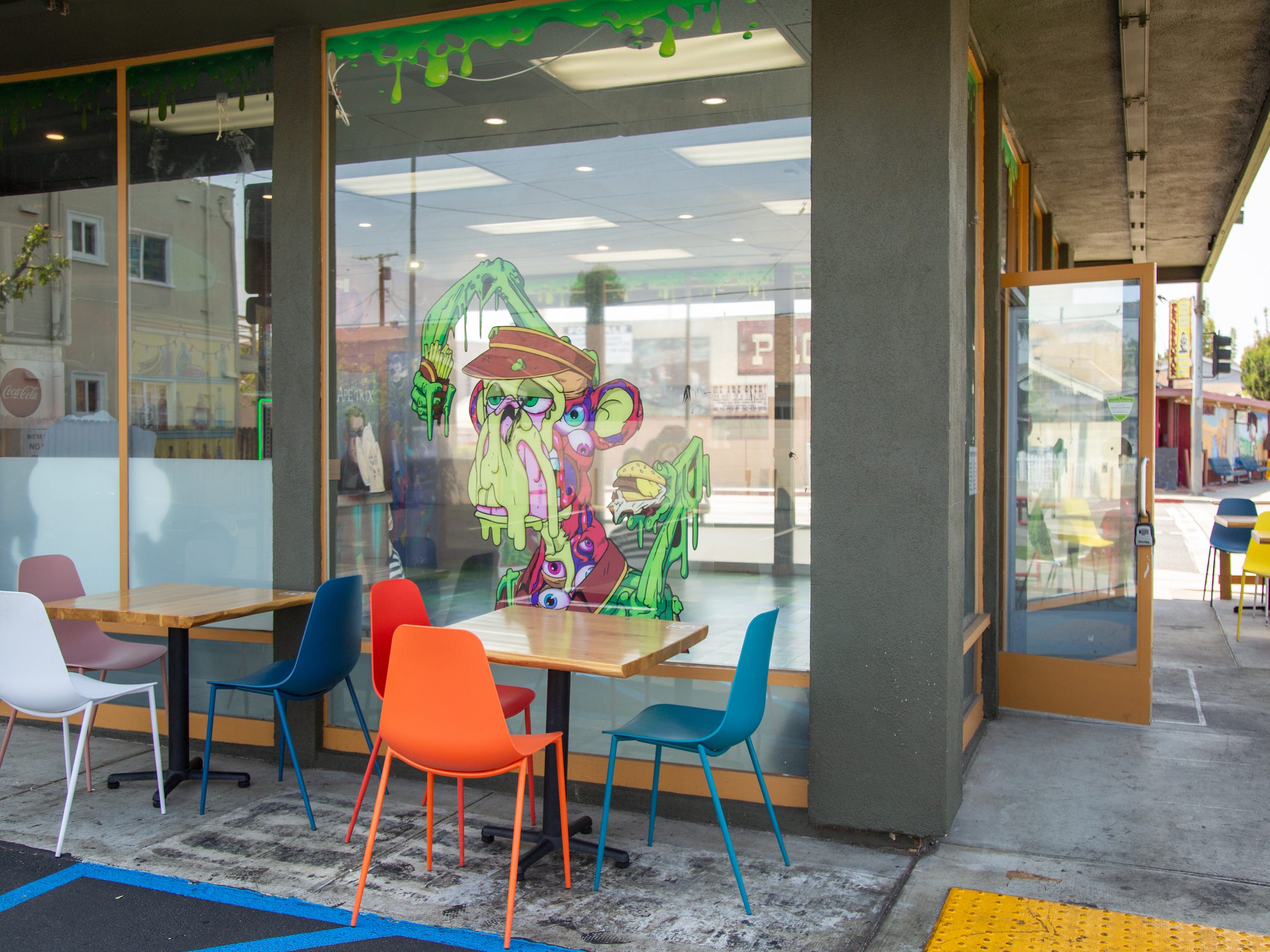 The exterior of the Bored and Hungry store with tables, chairs, a mutant ape decal.