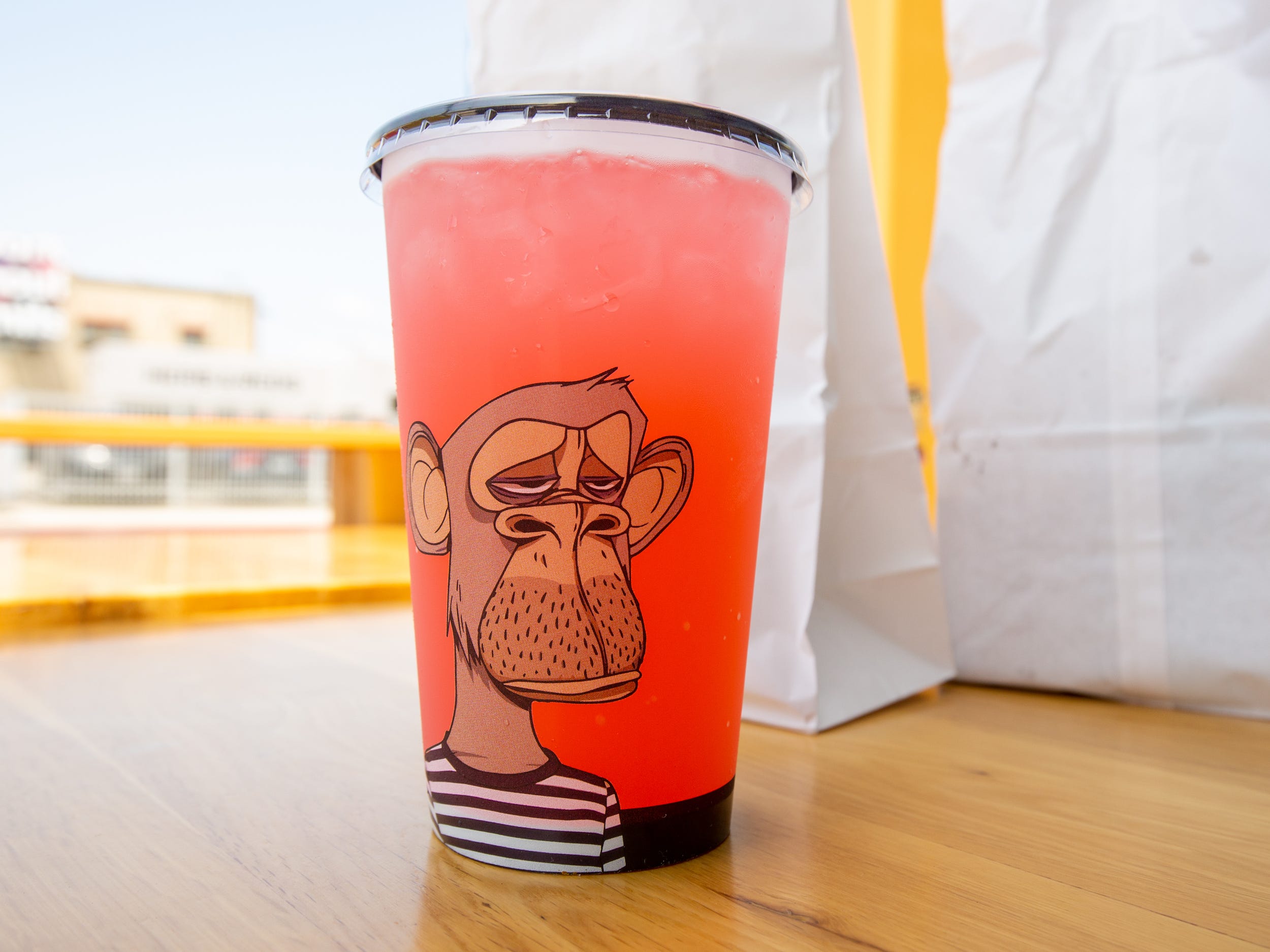 A pink beverage inside a plastic cup with an ape.