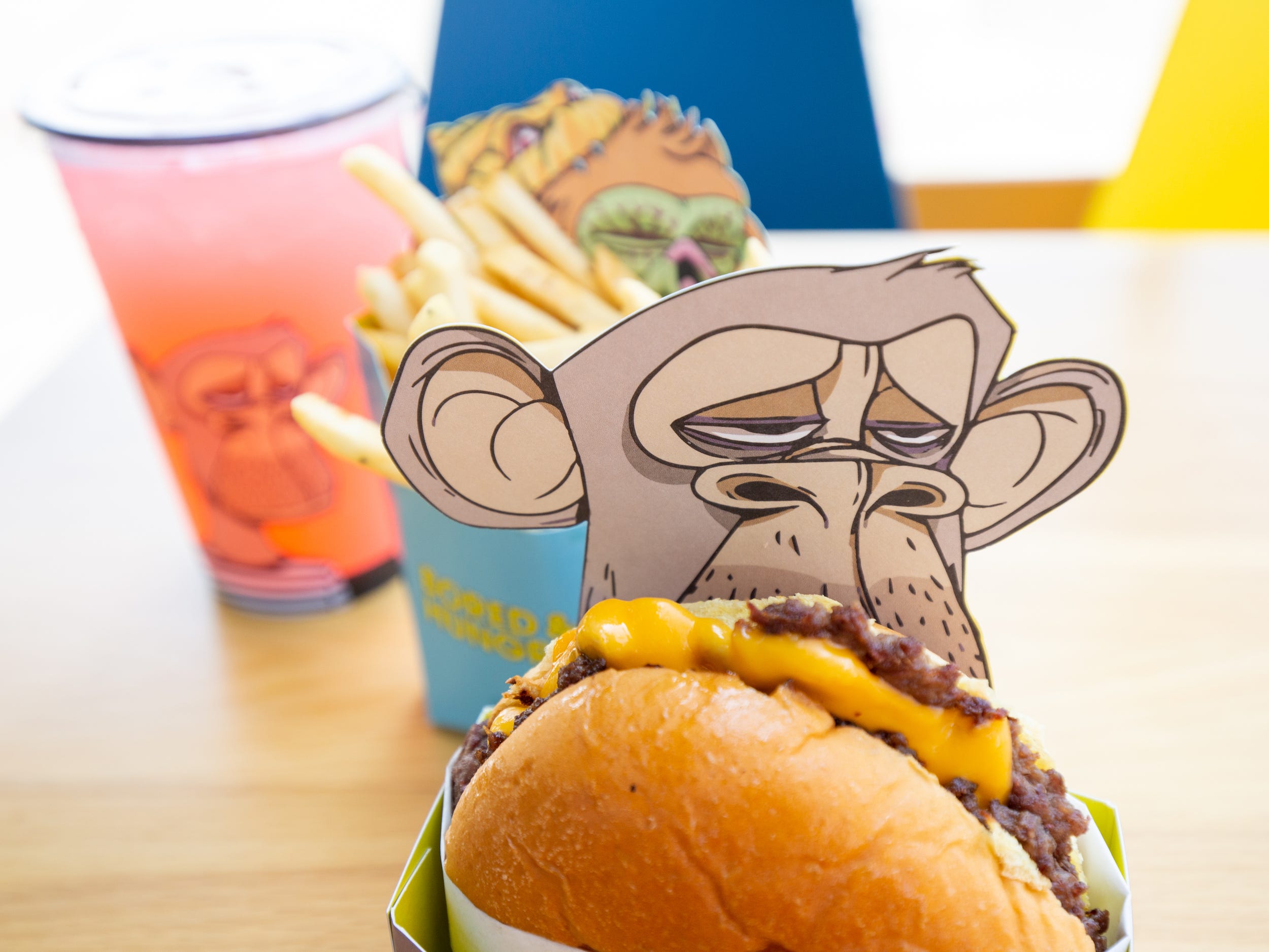 Burgers, fries, a pink drink all in ape branded Bored and Hungry packaging.