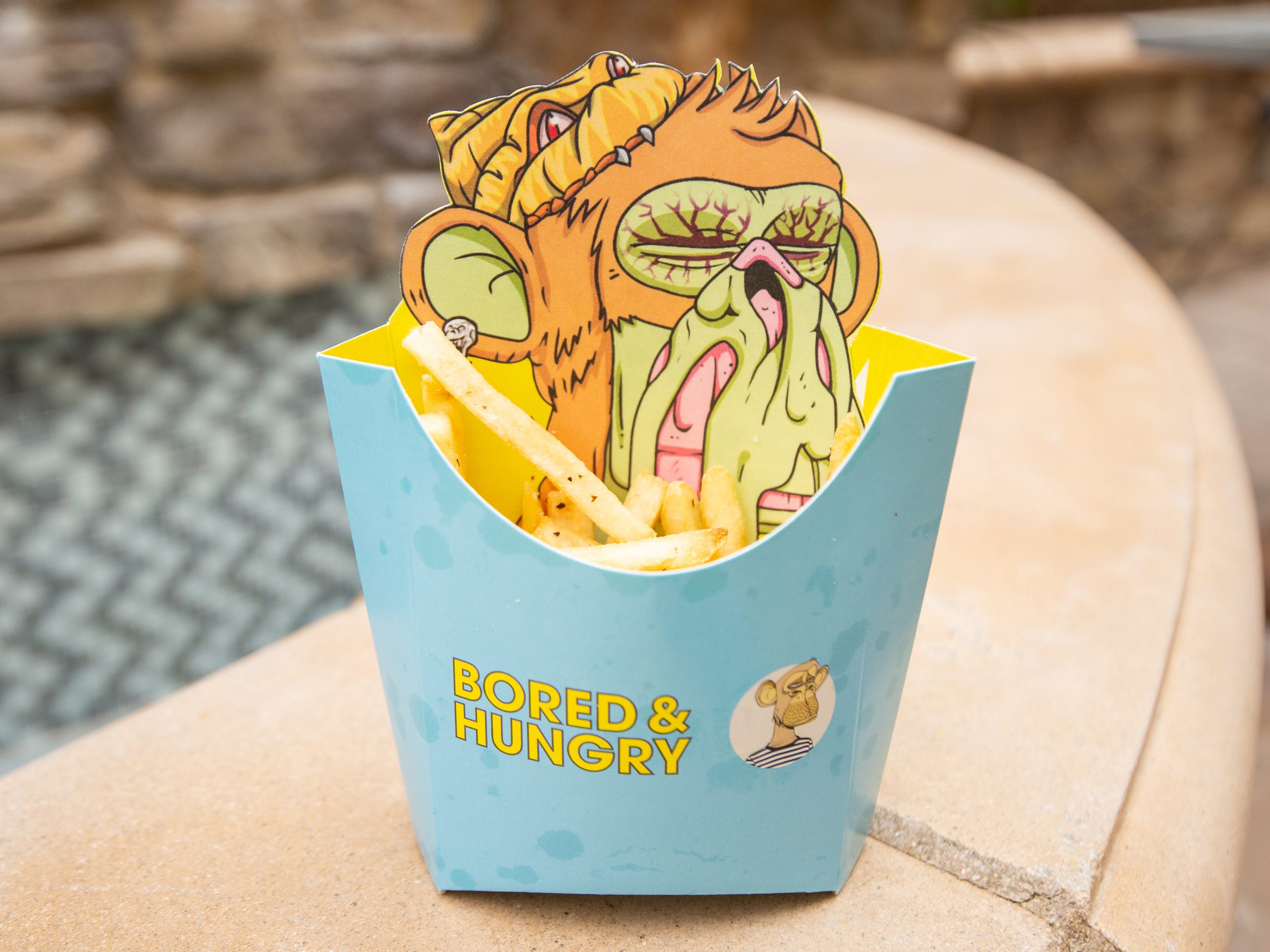 Fries inside of a Bored and Hungry container with an ape on the packaging.