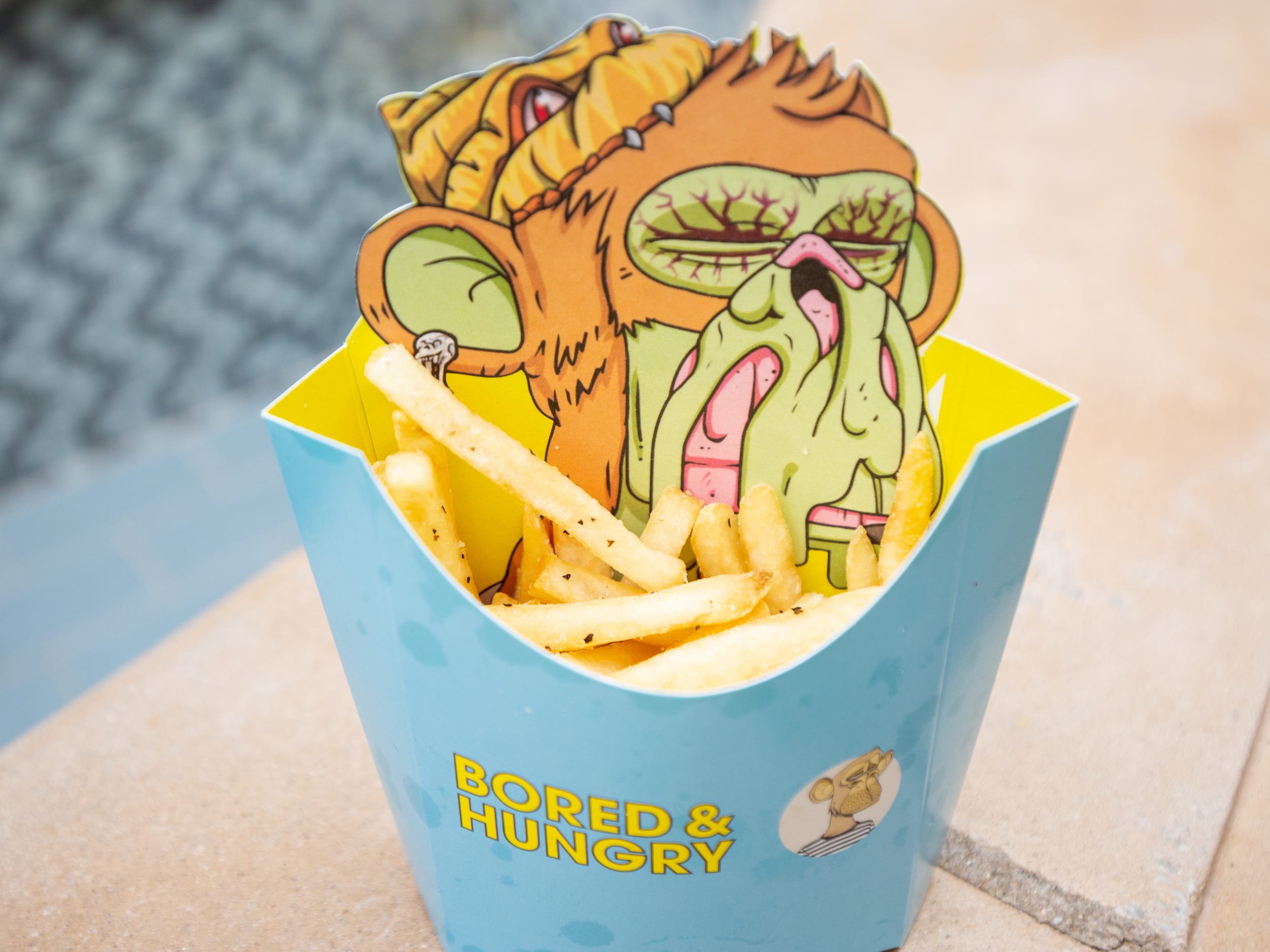 Fries inside of a Bored and Hungry container with an ape on the packaging.