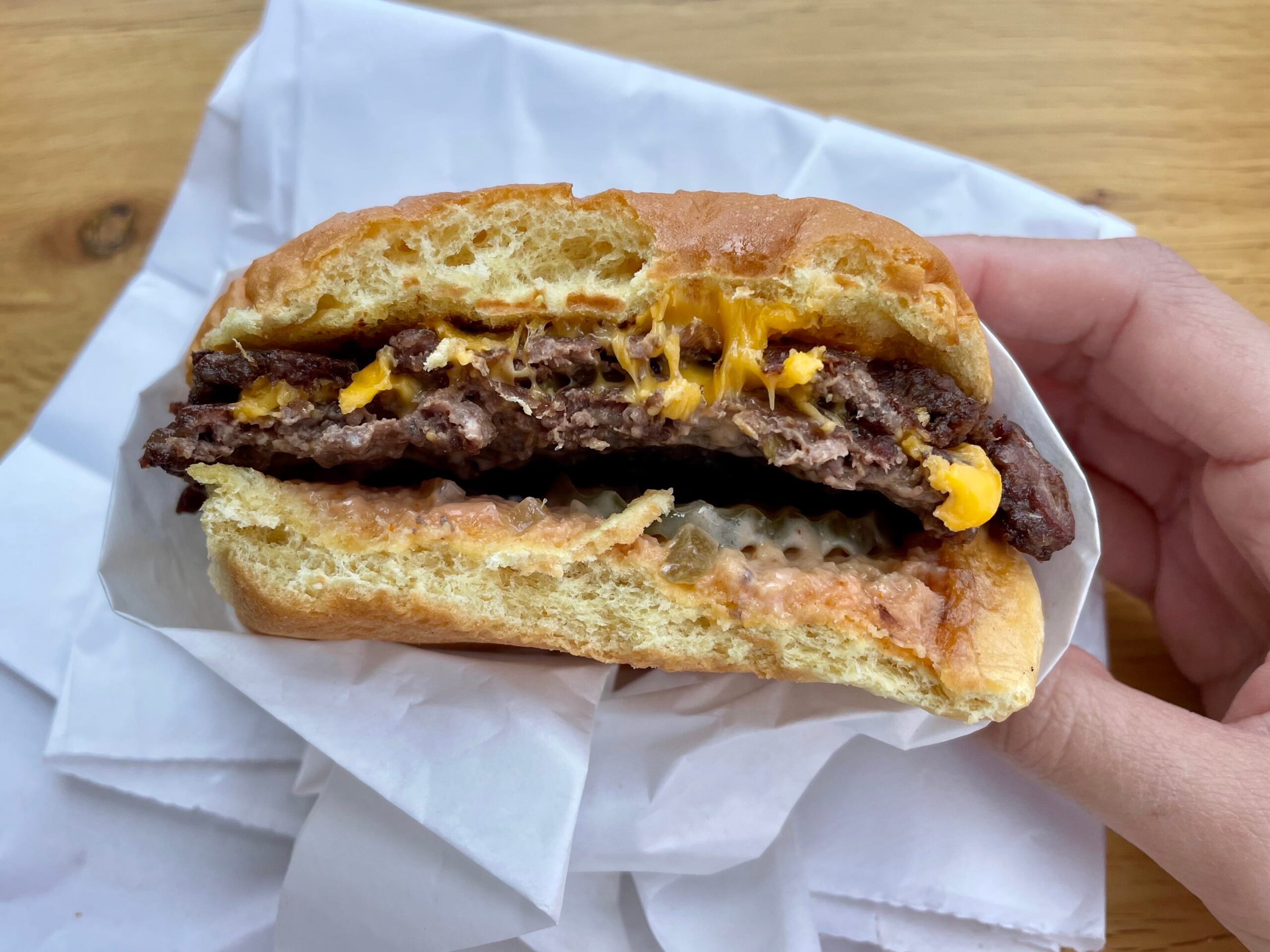 A half-eaten smashburger held against the white packaging.