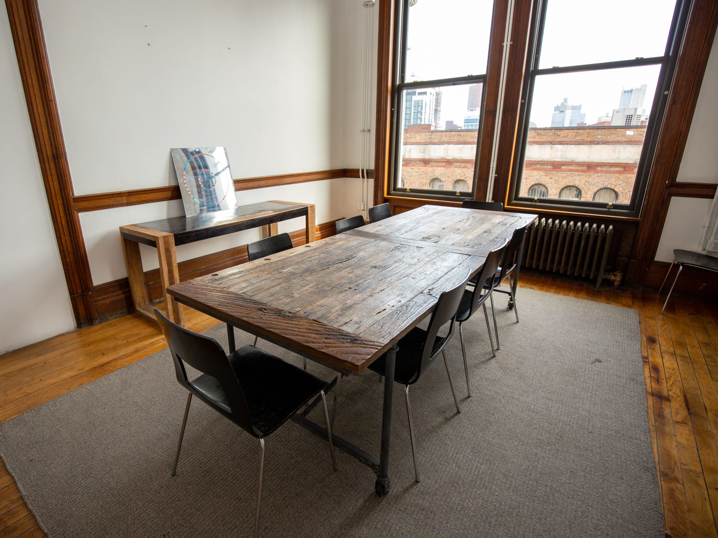 A room with a long wooden table, chairs near a window.