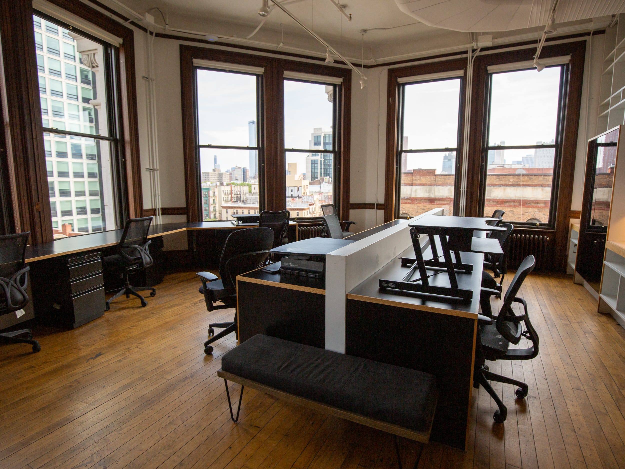 Long desks with office chairs, and windows with views of nearby buildings.