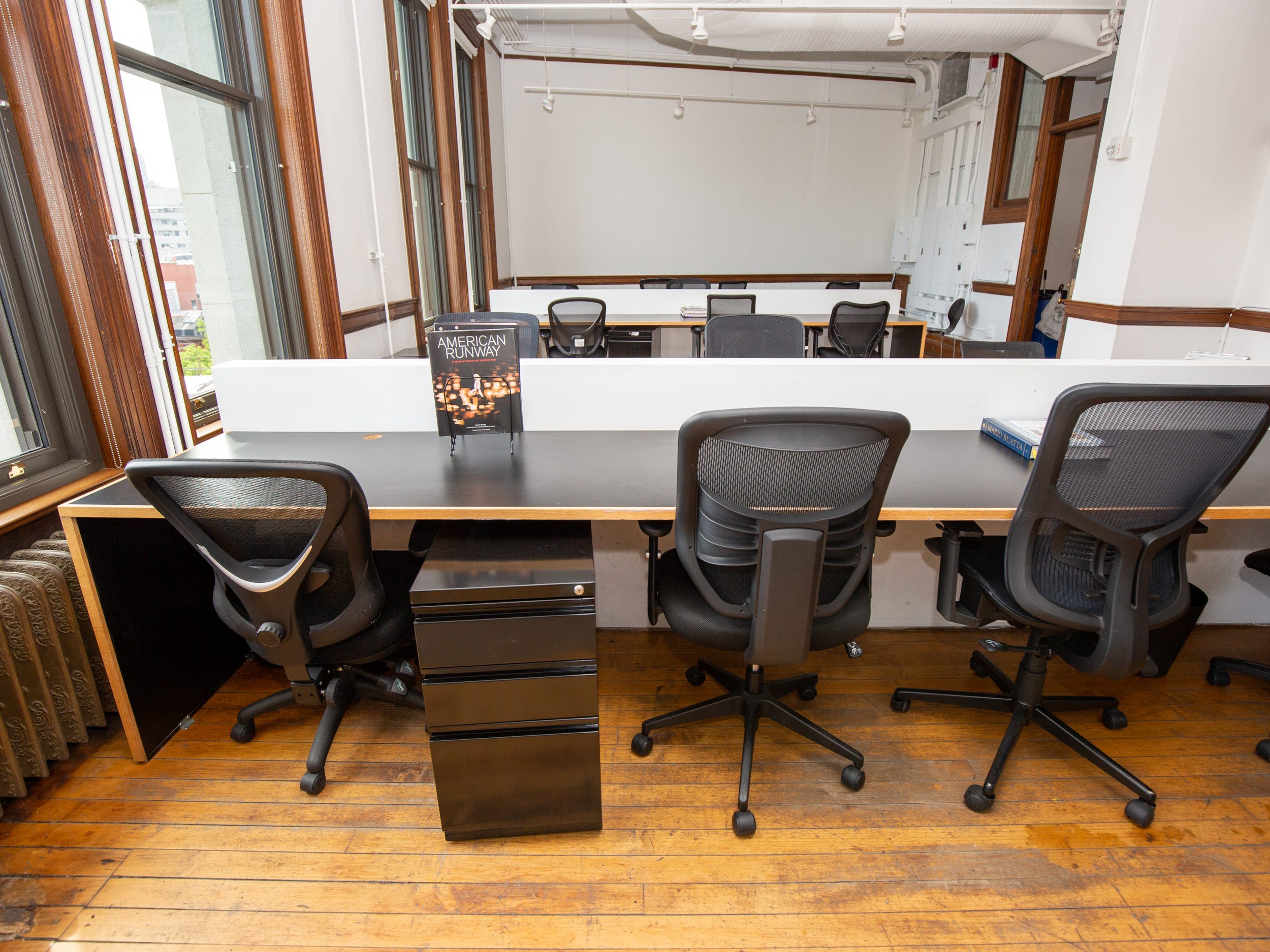 A room with rows of desk and chairs. The walls are empty.