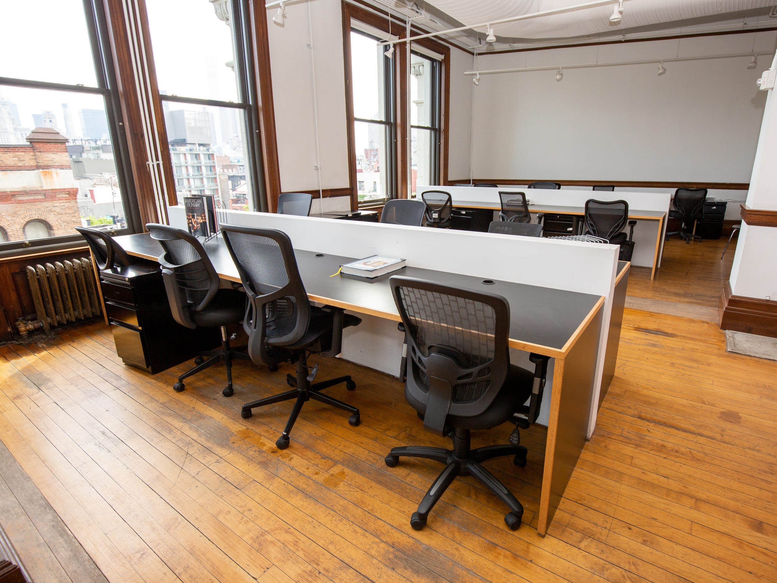 A room with rows of desk and chairs. The walls are empty.