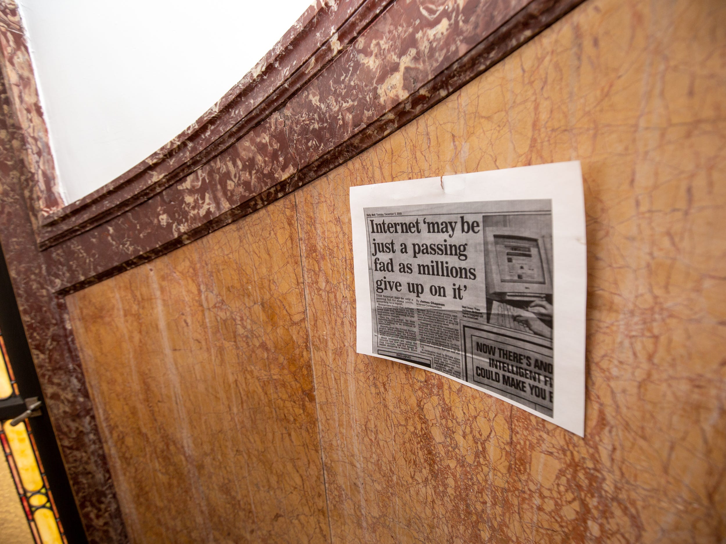 A piece of paper taped to the wall showing an old newspaper article with a headline that says "internet may be just a passing fas as millions give up on it."