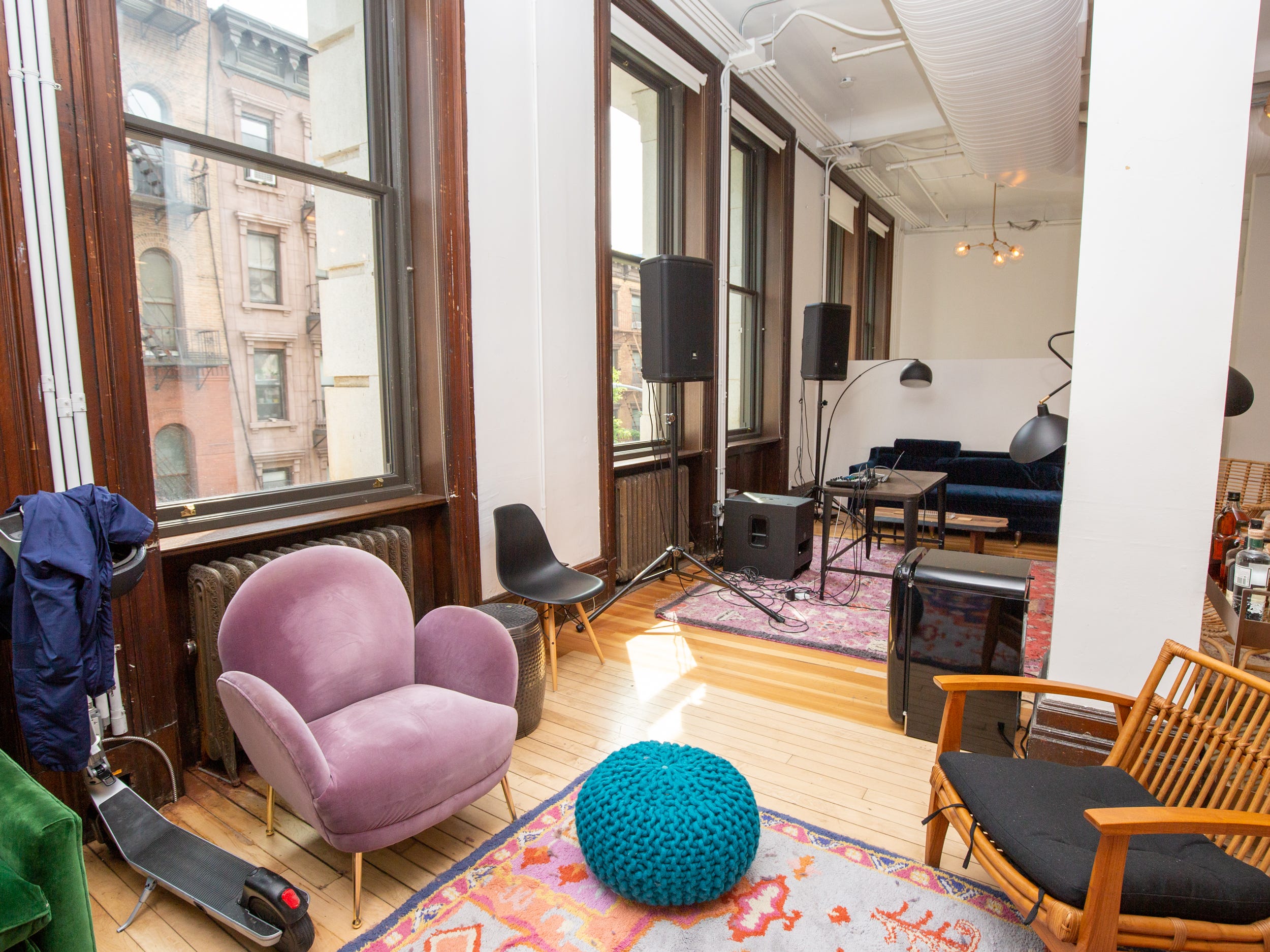 A room with large windows, a colorful rug, couches, chairs.