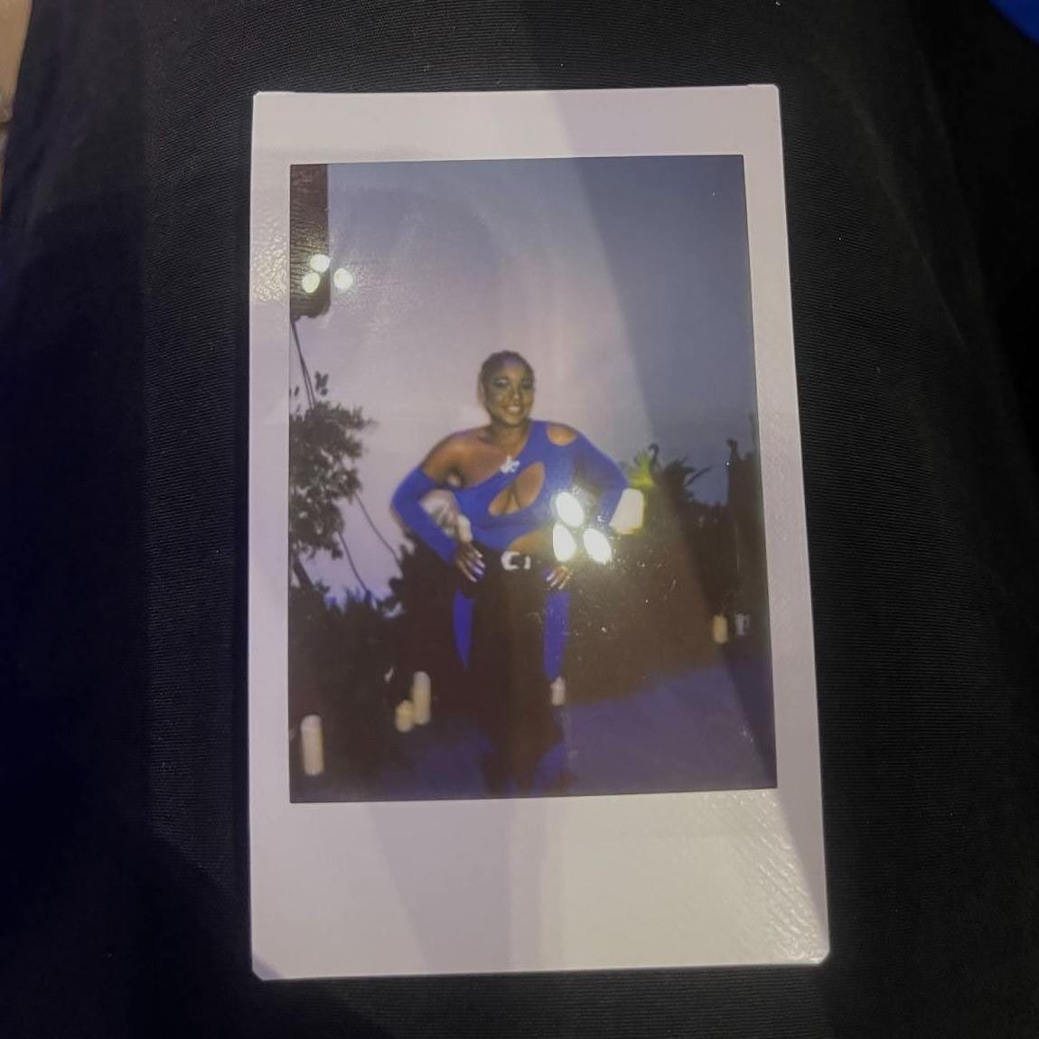 A photo of Kamira Roberson posing for a polaroid picture while wearing a blue cutout top.