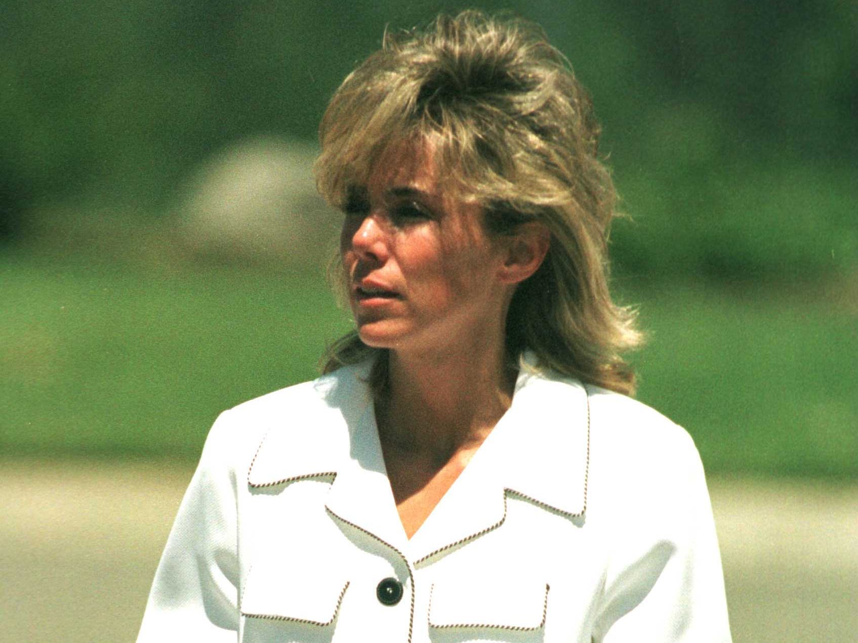 An image of a woman in a white jacket and trousers, holding a purse of money.